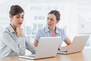 Worried businesswomen working on email etiquette at desk in office